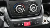 Car climate control panel: left knob for fan speed (1–4) and blue-to-red temperature, center area shows AC and airflow options, right knob selects directing vents; hazard light button centered below.