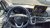 Car interior from the driver’s seat showing the steering wheel, gear shifter, climate controls, and a tablet mounted on the dashboard in a yellow case