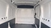 Interior of an empty white cargo van with black lower wall panels and a rubber floor.