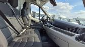 Front interior of a white van showing captain seats, steering wheel, and dashboard with a tablet mounted on the center console.