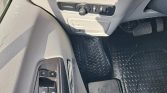 Driver's door with window and lock controls; beige interior, rubber floor mat, pedals visible in front of console.