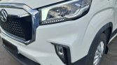 Close-up of the front left corner of a white SUV, showing the headlight, grille, and front bumper.