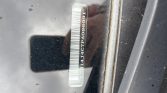 VIN sticker on a car windshield with a vertical barcode and visible alphanumeric VIN characters