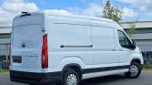 White cargo van parked on a paved lot, viewed from the rear and side with closed rear doors and a long side panel.