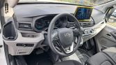 Interior of a car with steering wheel, digital gauge cluster, and a tablet-style infotainment screen on the dashboard.