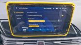 Infotainment screen in a car showing Driving Assist settings (Front/Forward Collision Warning, FCW On) with a yellow protective frame around the display.