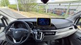 Interior of a car cockpit featuring a tablet mounted on the dashboard above the center stack, with steering wheel and gear selector in view.
