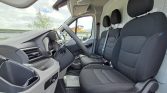 Interior of a van cabin with a left-hand steering wheel, driver and two front passenger seats, dashboard, and textured floor mat.