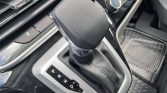 Automatic gear shifter in a car, showing P, R, N, D on the gear indicator with leather boot and center console nearby