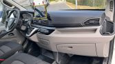 Front interior of a van with steering wheel, dashboard, climate controls, and a mounted tablet on the dash.