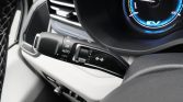 Close-up of a car steering-column stalk showing windshield wiper controls (HI/LO/AUTO/OFF) and a turn signal switch, with the instrument cluster in the background.