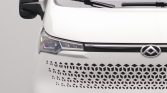 White van front close-up showing honeycomb grille and emblem (logo) on the grille area, left headlight visible