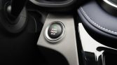 Push‑to‑start engine button on a car's center console, with a green status light