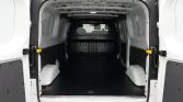 Empty white cargo van with rear doors open, showing a dark rubber floor and wheel wells along the sides.