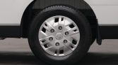 Close-up of a silver wheel hubcap with a circular center emblem on a black-tired van wheel.