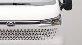 Front view of a white vehicle showing a honeycomb perforated grille and the emblem near the center.