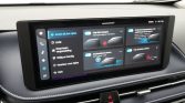 Infotainment touchscreen in a car showing driver-assistance options and controls in Dutch on a dark UI.