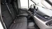 Front cabin of a white van with two black fabric seats, a steering wheel, and a touchscreen dashboard.