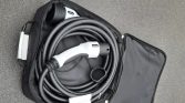 Electric vehicle charging cable neatly coiled inside a black carrying case with a white charging plug visible at the top.