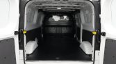 Empty white cargo van interior with a dark floor, side panels, and a translucent rear window; open rear doors reveal a spacious, uncluttered loading area.
