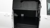 Open white cargo van with empty black cargo area and ramp door, viewed from the side with the side door open