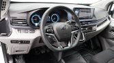 Interior view of a car dashboard with a steering wheel, digital instrument cluster, and a wide center touchscreen display.