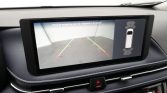 Car dashboard screen showing rearview camera with guiding lines; proximity sensor diagram on the right.