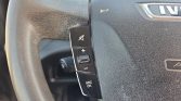Close-up of car steering wheel buttons: mute icon, volume up/down, SRC/OK button for media controls on the left side of the wheel