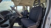 Inside a white truck cab showing the driver and front passenger seats, steering wheel, and dashboard.