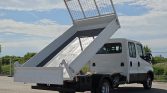 White dump truck with its bed raised, ready to unload on a paved lot.