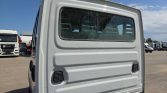 Back view of a white truck cab in a parking lot, showing the window, rear panel with two vents, and part of the chassis.