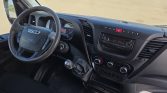 Interior of a van cab with steering wheel, manual gear shift, and dashboard controls in view near the driver seat.