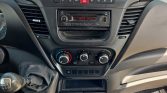 Car dashboard center with a radio showing 97.7 MHz and climate control knobs below the display panel