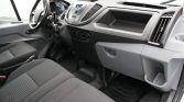 Front interior of a commercial van: black dashboard, steering wheel, center console, and two front seats with gray fabric. A tablet is mounted on the windshield above the dashboard.