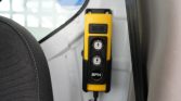 Yellow handheld control panel with up and down arrow buttons mounted on a vehicle interior (SPX label) for operating a mechanism.
