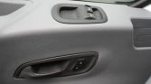 Grey car door interior with a window switch cluster and a door handle featuring lock/unlock buttons.