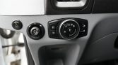 Close-up of a car's driver-side dashboard with a round headlight/lighting control dial and fog light switch on textured gray plastic state.