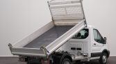 White utility/work truck with a raised metal dump bed, showing a tilted cargo bed ready to unload.
