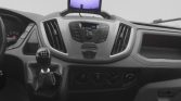 Vehicle interior: manual gear shift, center console with climate controls, and a mounted display screen above the dashboard.
