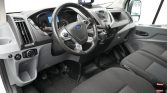 Interior of a Ford van cockpit with steering wheel, gear shifter, and dashboard controls visible