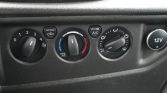 Car climate control panel: leftmost dial for fan speed, middle dial for temperature with blue to red, right dial for airflow direction; recirculation and A/C buttons visible; 12V power outlet on the right