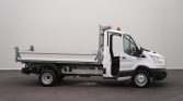 White flatbed utility truck with orange beacon; driver’s door open, shown indoors.