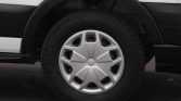 Close-up of a car wheel with a silver hubcap and black tire, showing the fender above it.