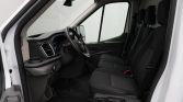 Front cab of a white van with black dashboard, steering wheel, and three seats visible from the open driver's side door, showing the driver's area and passenger row.