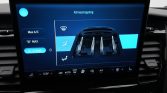 In-car touchscreen showing climate control interface: left column buttons for Max A/C, MAX, E-Heat; central blue panel with a car vent diagram and seat icons; bottom status bar remains visible.