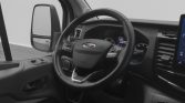 Interior of a Ford van showing the steering wheel, dashboard instruments, and left-side mirror