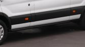 White cargo van shown from the side with a black lower trim, orange side reflectors, and a visible wheel tucked under the fender.