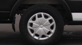 Close-up of a silver hubcap on a black-tired wheel under a dark vehicle fender.
