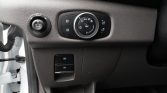 Car dashboard close-up showing headlight control dial, fog light buttons, and electronic parking brake switch.