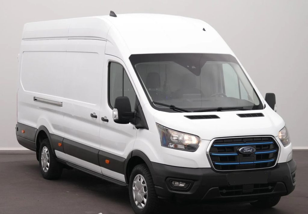 White Ford cargo van with high roof, black bumper, & side mirrors parked indoors, front grille visible.